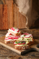 Board with delicious radish bruschettas on wooden table