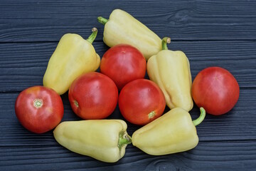 pile on a fresh green bell pepper and red tomatoes lie on a black wooden table