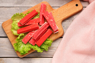 Board with tasty crab sticks on light wooden background © Pixel-Shot
