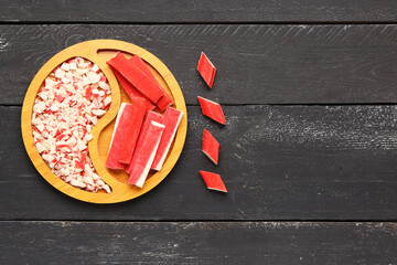 Plate with tasty crab sticks on dark wooden background © Pixel-Shot