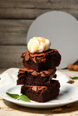Plate with pieces of tasty chocolate brownie and ice cream on light wooden background