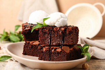 Plate with pieces of tasty chocolate brownie and ice cream on table