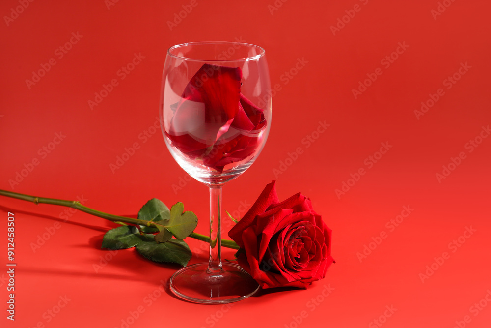 Wall mural Glass with petals and beautiful rose on red background