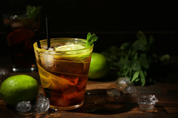Glass of tasty Cuba Libre cocktail on dark wooden background
