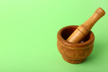 Wooden mortar and pestle on green background