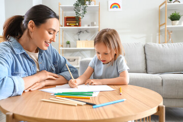 Young woman with her little daughter drawing at home