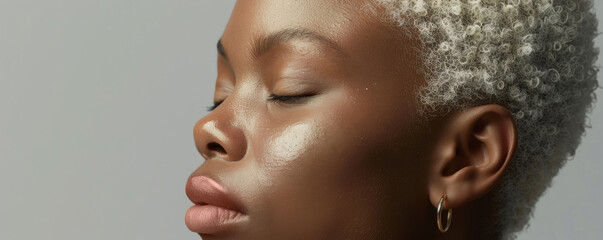 An African American model with fair skin and white hair poses in a minimalist studio, celebrating the unique beauty and diversity in her features