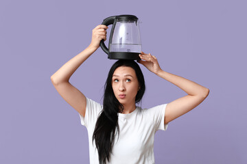 Funny young woman with modern electric kettle on lilac background