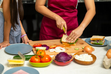 Happy Asian family spending time together. Mother and little daughter making sandwich for breakfast in the kitchen. Mom and child girl kid enjoy indoor lifestyle cooking and eating food at home.