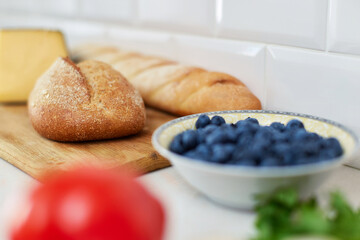 Homemade rye bread and blueberries in glass bowl on white table. Healthy eating