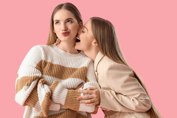 Young lesbian couple on pink background