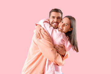 Fototapeta premium Happy young couple in casual clothes on pink background