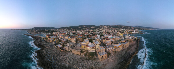 Panoramic sunset view of Batroun, Lebanon, showcasing the coastal city's blend of ancient walls, modern buildings, and picturesque shoreline along the Mediterranean Sea