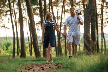 Fototapeta premium With acoustic guitar. Lovely couple are together in the forest at summer daytime