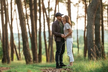 Fototapeta premium Looking at each other. Lovely couple are together in the forest at summer daytime