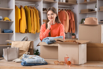 Beautiful young happy woman unpacking wardrobe boxes with stylish clothes in dressing room