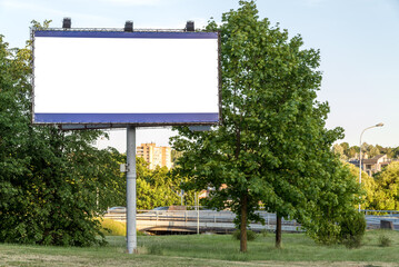 Blank Big Billboard Mockup In A City Natural Landscape. Modern Style advertisement on a pole close to a park with green trees