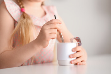 Cute little girl with yogurt at home