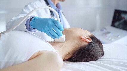 Doctor man wearing blue medical gloves is using ultrasound equipment on neck of female patient lying down for a medical examination