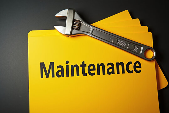 Yellow folders with the printed word 'Maintenance' on the cover and a spanner on top. Concept on maintenance schedule for equipment, machinery servicing, fault repair reports, or upkeep records.