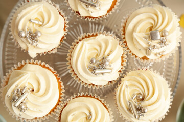 Dessert stand with tasty white cupcakes for birthday party on table, closeup