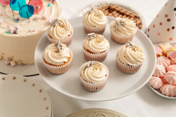Dessert stand with tasty cupcakes and other sweets for birthday party on white table