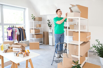 Male volunteer taking donation box from shelf in center
