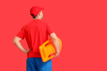 Handsome male lifeguard with life board on red background