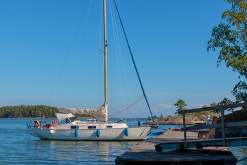 Sailboat tied to a mooring buoy at the harbor of the island in Finland, Baltic sea, Yacht in Shore marina in Baltic Sea, a safe anchorage for yachts and sail boats.