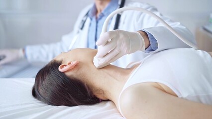 Obraz premium Doctor man is using ultrasound equipment on neck of female patient lying down for a medical examination. Medicine and science