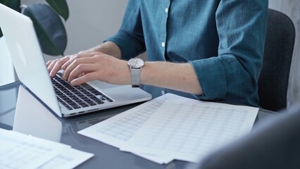 Professional casual dressed businessman is working on laptop at office grey and glass desk. Close-up of an adult's hands typing on a keyboard. Business people