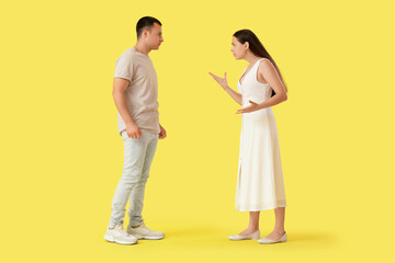 Young couple quarreling on yellow background