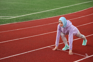 Fototapeta premium Sporty Muslim woman getting ready to run at stadium