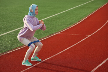 Fototapeta premium Sporty Muslim woman in headphones training at stadium
