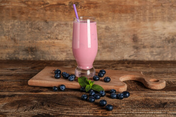 Glass of fresh blueberry smoothie with mint and berries on wooden background