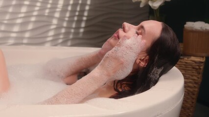 Relaxing Caucasian woman female girl lady emerge from hot warm water enjoying foamy bath at home bathroom bathtub washing head hair bathing spa stress recreation hygiene procedure body care routine