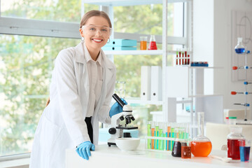 Female chemist with microscope on table in laboratory