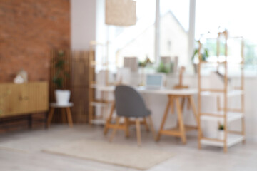 Blurred view of modern office with workplace, shelf units and window