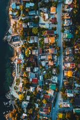 Fototapeta premium Bird's-eye view of a coastal city at twilight, with the last light of the day casting a golden hue over the colorful houses and streets. 