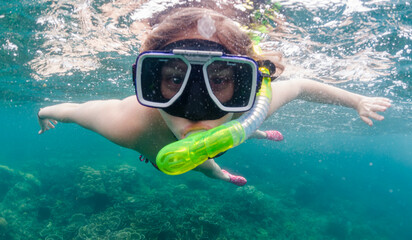 Young woman wearing a full face snorkel mask under water in the ocean