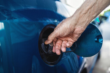 An unrecognized man opens the gas tank of a car to fill up with gas. Man opening car fuel tank, close up.