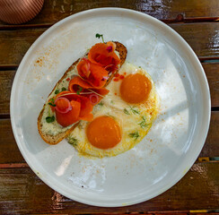 Smoked salmon on toast with fried eggs for breakfast at a restaurant while on vacation.