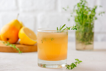 Pear lemonade with lemon, rosemary, thyme and ice on a light table. Healthy drink, sugar and alcohol free.