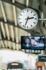 close up of clock at sky train terminal screen in the back and train is coming day time