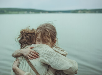 Fototapeta premium Mother hugging her child close on an overcast day at the beach