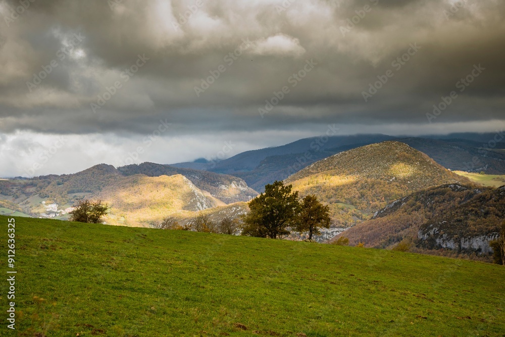 Sticker Picturesque landscape of rolling hills under a dramatic cloudy sky