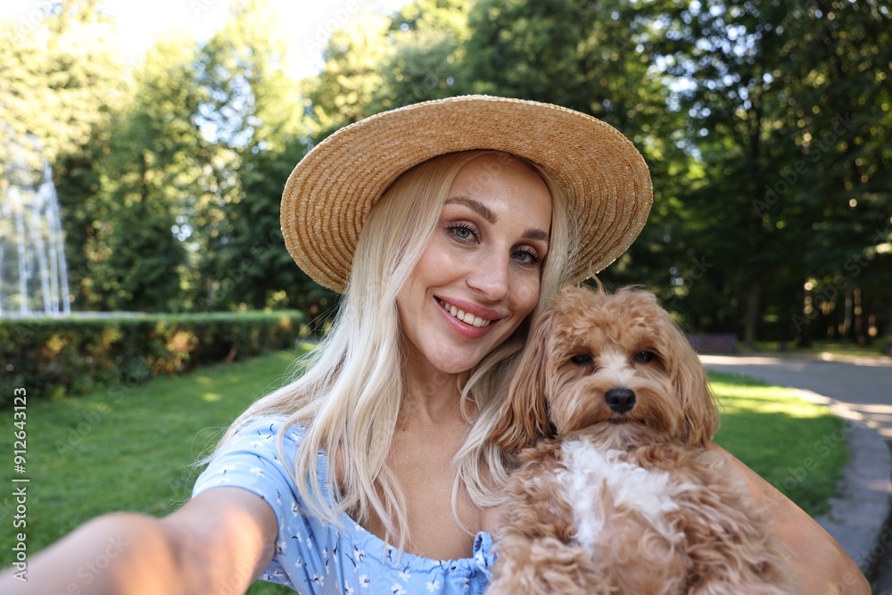 Wall mural Beautiful young woman taking selfie with cute dog in park