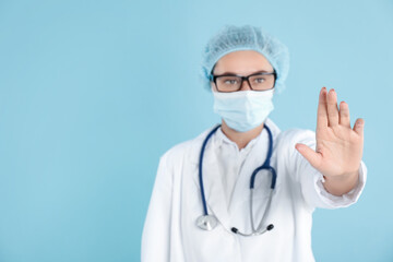 Doctor touching something on light blue background, selective focus. Space for text