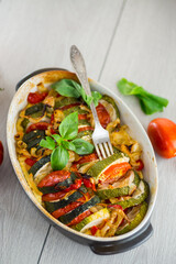 prepared baked zucchini and tomatoes in circles in a ceramic form, vegetable snack
