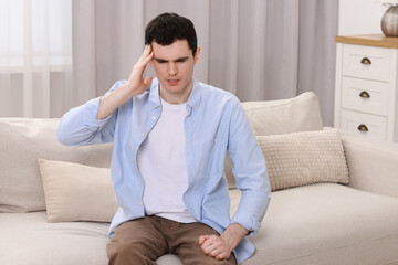 Fototapeta premium Man suffering from headache on sofa at home